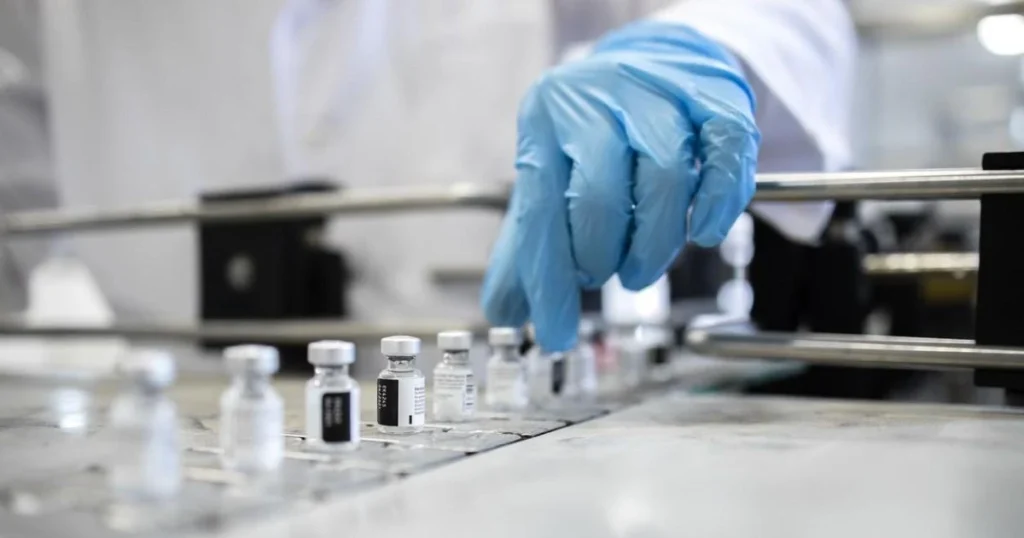 gloved hand selecting vax vial 0 0
